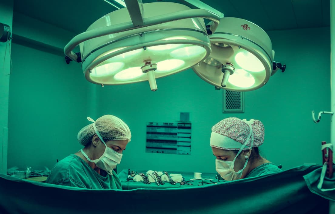 Two surgeons under surgical lights concentrating on a surgery, with medical equipment