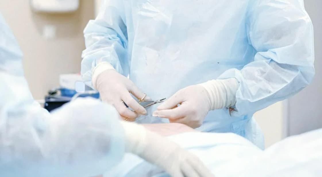 Medical professionals in a sterile environment handing off surgical tools during an operation